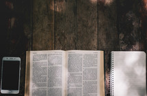 cellphone, open Bible, notebook, on a wood background 