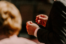 Close up of a man's hands holding broken bread and cup of juice during communion.