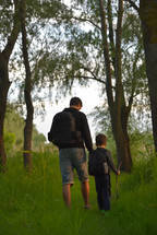 Father and son walking into the forrest at sunset