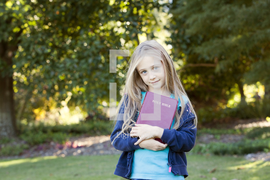 Young girl with Bible outdoors