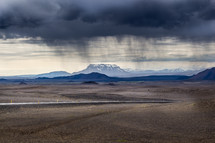 rain sheers from gray clouds over desert mountain landscape  