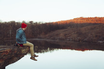 a man sitting on a rock over a lake 