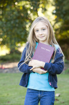 Kid holding the Bible outdoors