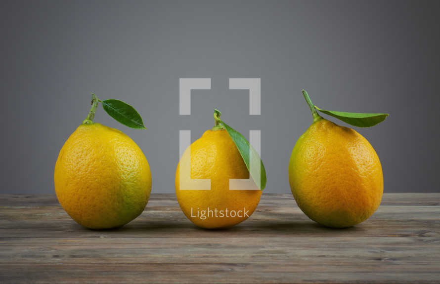 A row of three lemons in a row on a table.