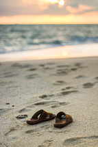 sandals and footprints in the sand on a beach 