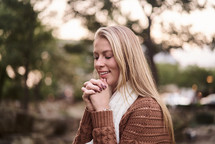 a woman in a sweater with praying hands 