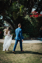 bride and groom walking across a lawn