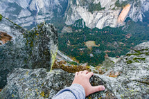 hand at the edge of a mountain cliff 