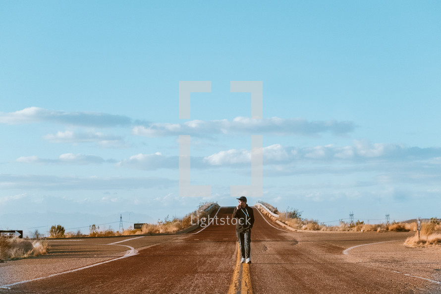 a man walking down the middle of a rural road 