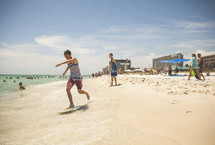 teen boy skim boarding on the beach 