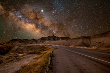 milky way and stars over a lonely desert road at night 