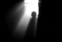 a child sitting in sunlight through a window 
