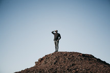 a man searching standing on a rocky hill 