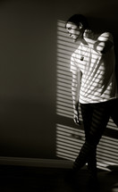 young man posing in sunlight through blinds 