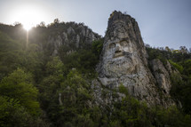 a face carved into rock on a cliff 
