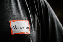 a man wearing a name badge with the word volunteer 