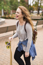 teen girl walking to class carrying a skateboard 