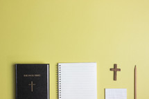 Bible and notebook on a yellow background 