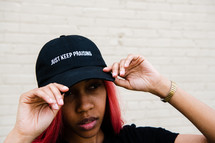 portrait of a young African American woman with Just Keep praising hat 