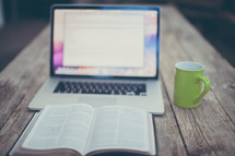 open Bible, computer screen, and coffee mug 