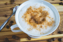 Delicious home made Cappuccino, in a white cup, on a wooden table. With coffee beans. Home made Coffee.