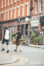 pedestrians walking on a downtown street in front of a flower shop 