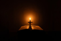 Candlelight photo of a Bible and cross