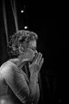 A woman with her hands pressed together in prayer.