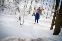 a woman with her hands raised standing in the snow
