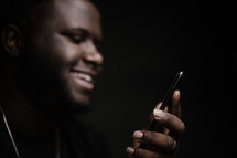 a man smiling looking at his cellphone 