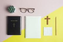 Bible and notebook on a pink and yellow background 