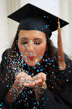 a female graduate blowing confetti 