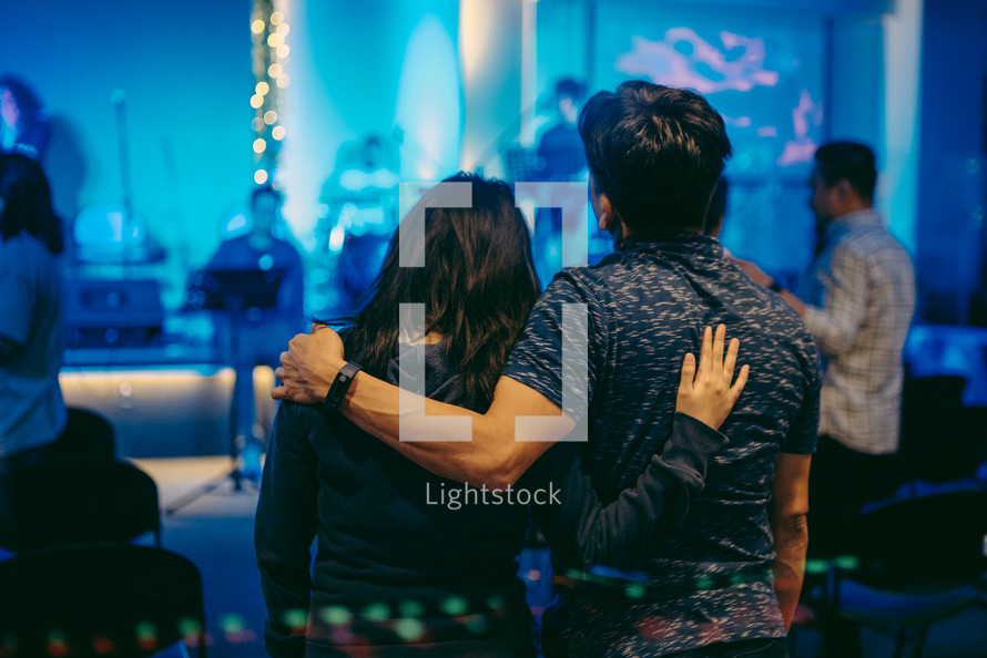 a couple with arms around each other during a worship service 
