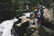 hikers standing on a rocks near a waterfall 