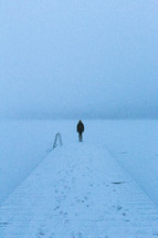 standing at the end of a snowy dock on a frozen lake 
