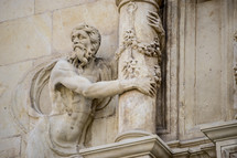 stone statue grasping a column 