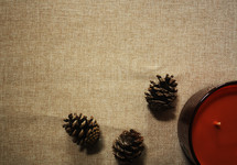 pine cones and candle on burlap background 