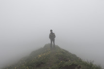 a boy standing on a hill in the fog 