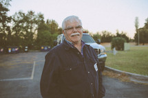 man with a white mustache standing outdoors 