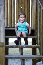 A little girl sitting on wooden steps.