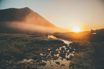 fog in a mountain valley and stream at sunrise 