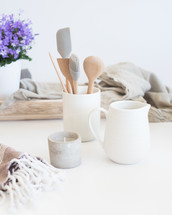 kitchen utensils, ceramic, kitchen, tools, countertop, jar, house plant, wood tray, linen fabric, votive candle, pitcher