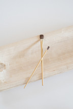 Two artist paintbrushes on a wooden plank.
