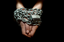 Prisoner's hands and arms chained up with lock.