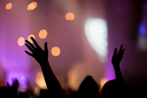 silhouettes of raised hands in an audience 