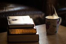 stack of books and steam from a mug 