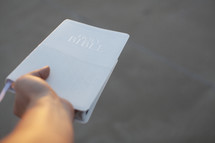 hand holding out a Bible 