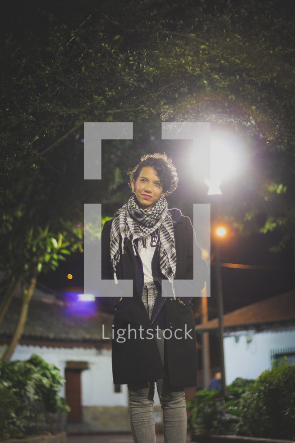 woman standing under a street lamp at night 
