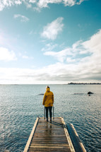 a woman in a rain jacket standing on a dock