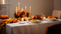 A beautiful table with Thanksgiving dinner served, turkey, mashed potatoes, a pumpkins topped of with candle lights, 